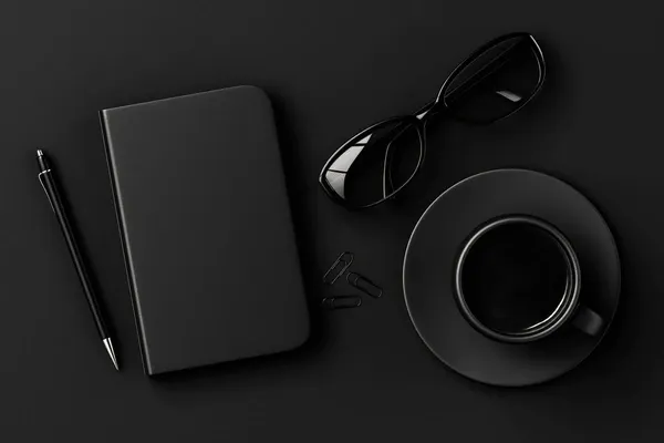 A dark desk flatlay with a notebook, glasses, and a cup of coffee.
